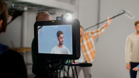 Actors-Shooting-Movie-Or-Video-In-Studio-With-Film-Crew-And-Female-Director-Watching-Monitor-In-Foreground-1